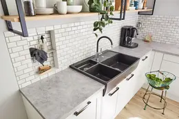 Cuisine lumineuse de style campagnard avec &eacute;vier gris fonc&eacute;, cr&eacute;dence en carrelage blanc et niche murale KERDI-BOARD carrel&eacute;e.