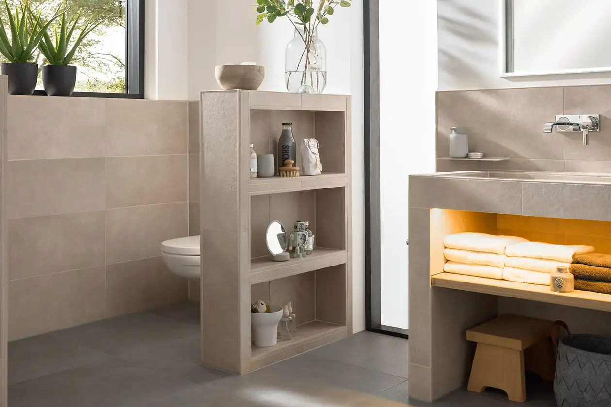 Salle de bains beige avec plan vasque Schlüter-KERDI-BOARD-W et cloison de séparation de sanitaires en KERDI-BOARD.