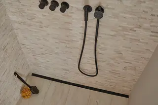 Douche &agrave; l'italienne avec carrelage de couleur sable, robinetterie noire et caniveau filant Schl&uuml;ter-KERDI-LINE-VARIO en noir mat.