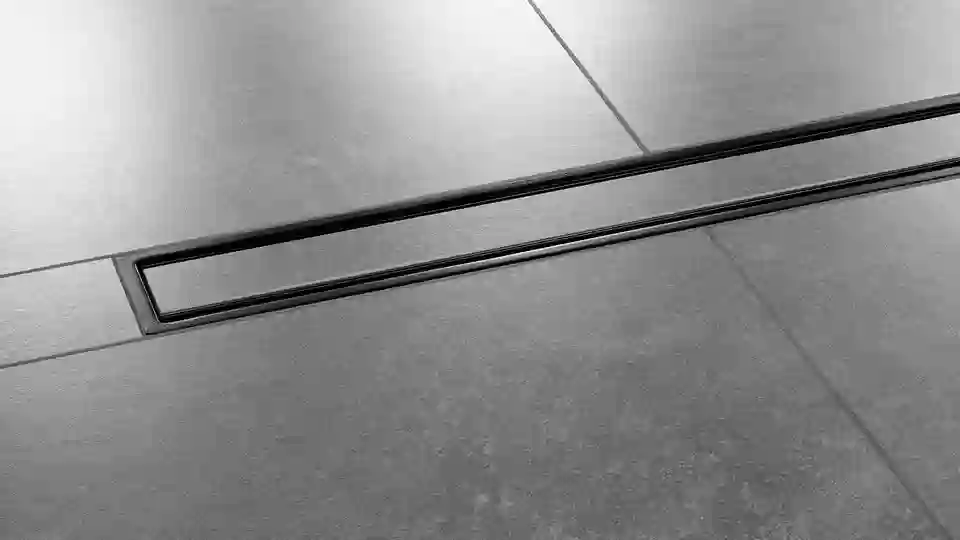 Gros plan sur un sol de douche avec carrelage de couleur gris foncé et caniveau Schlüter-KERDI-LINE-C installé au centre de la douche, design FRAMED TILE, finition TRENDLINE, noir graphite mat.