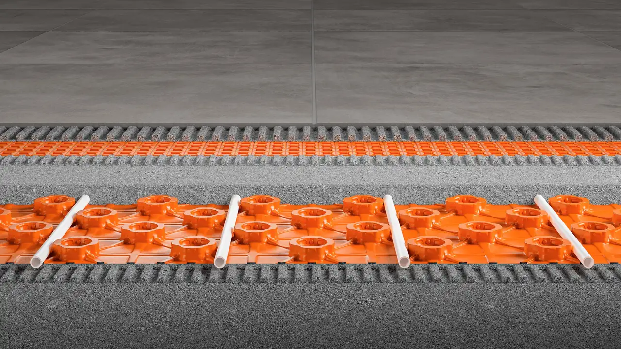 Représentation en coupe d'une structure au sol avec la dalle à plots Schlüter-BEKOTEC-EN-FK et la natte de désolidarisation Schlüter-DITRA, recouverte de grands carreaux de céramique gris pierre.