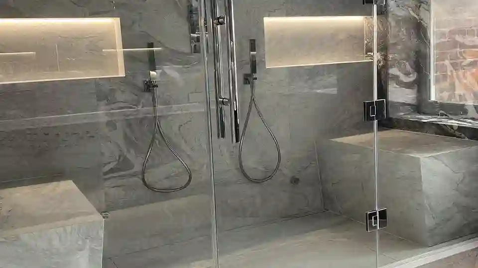 Un espace douche dans le hammam avec deux assises, deux niches et deux douches de chaque côté