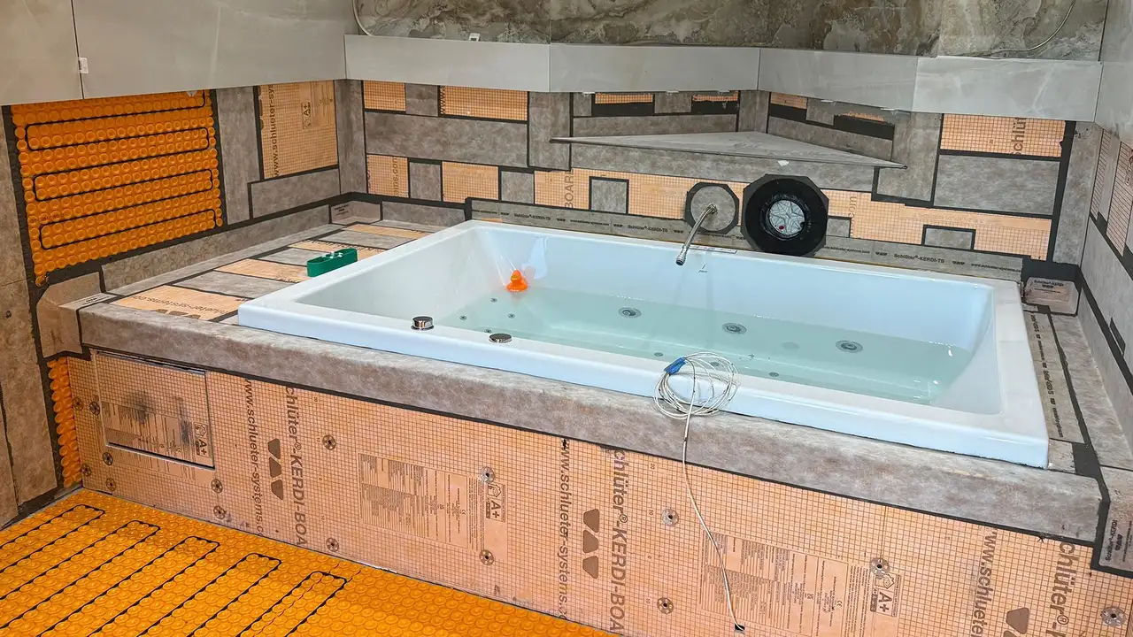Construction of a bathtub with visible below the tiles installations such as waterproofing membranes and electric heating