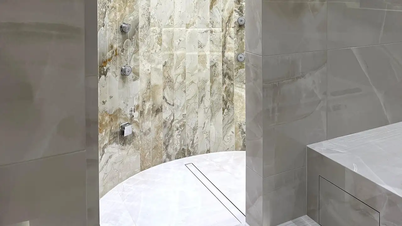 Entrance into a steam room between two walls with large light grey and marble tiles