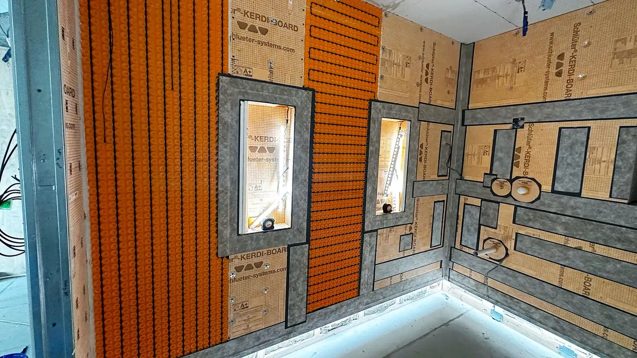 Bathroom construction site with LED-lit wall niches, orange uncoupling mat and heating cables on the wall