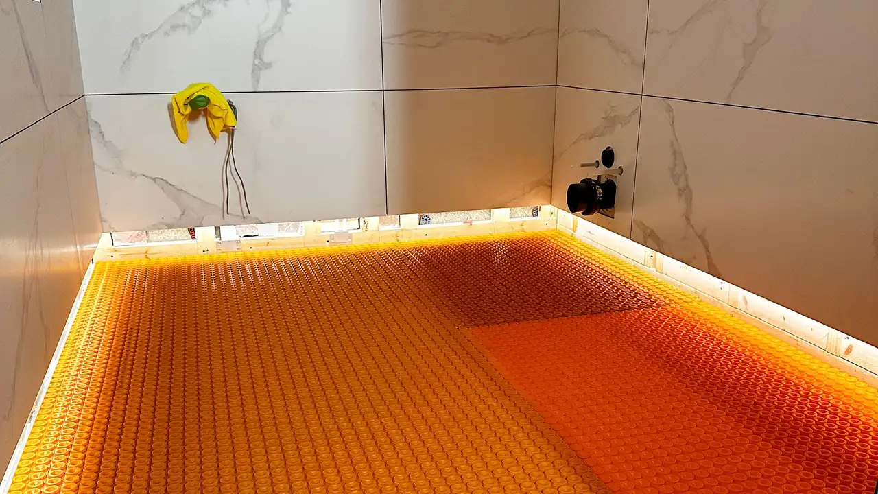 Shower area with installed orange uncoupling mat