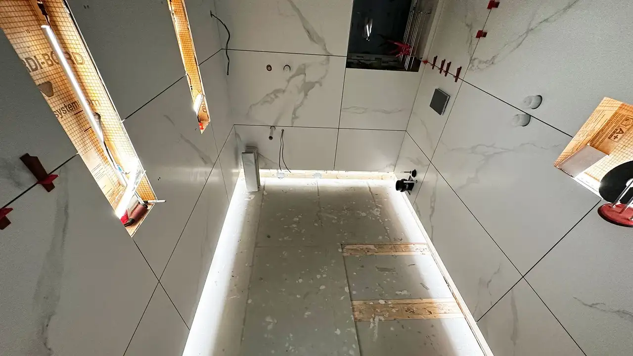 Shower area with large format marble tiles and LED-lit wall niches