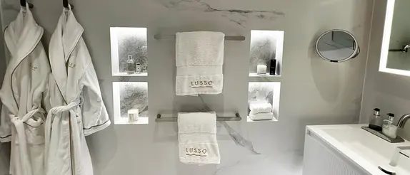 Bathroom wall with four LED-lit wall niches, robes and towels