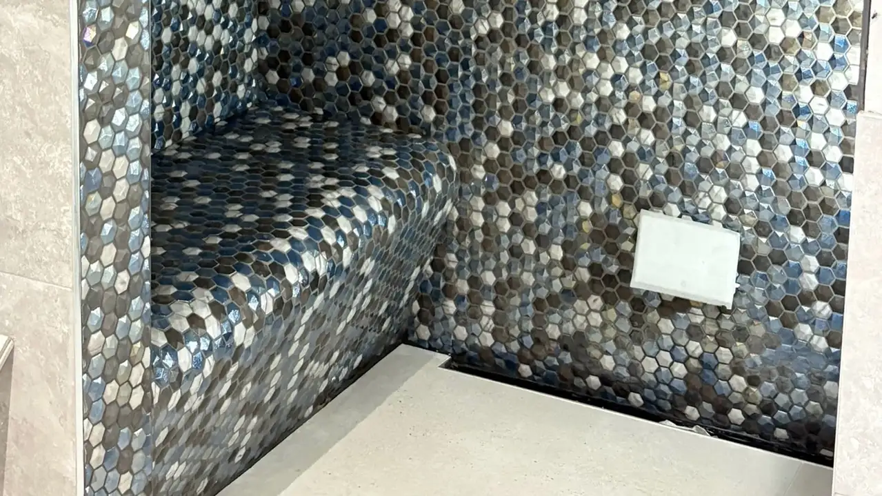 Bench in a shower tiled with blue, white and grey hexagon shaped tiles