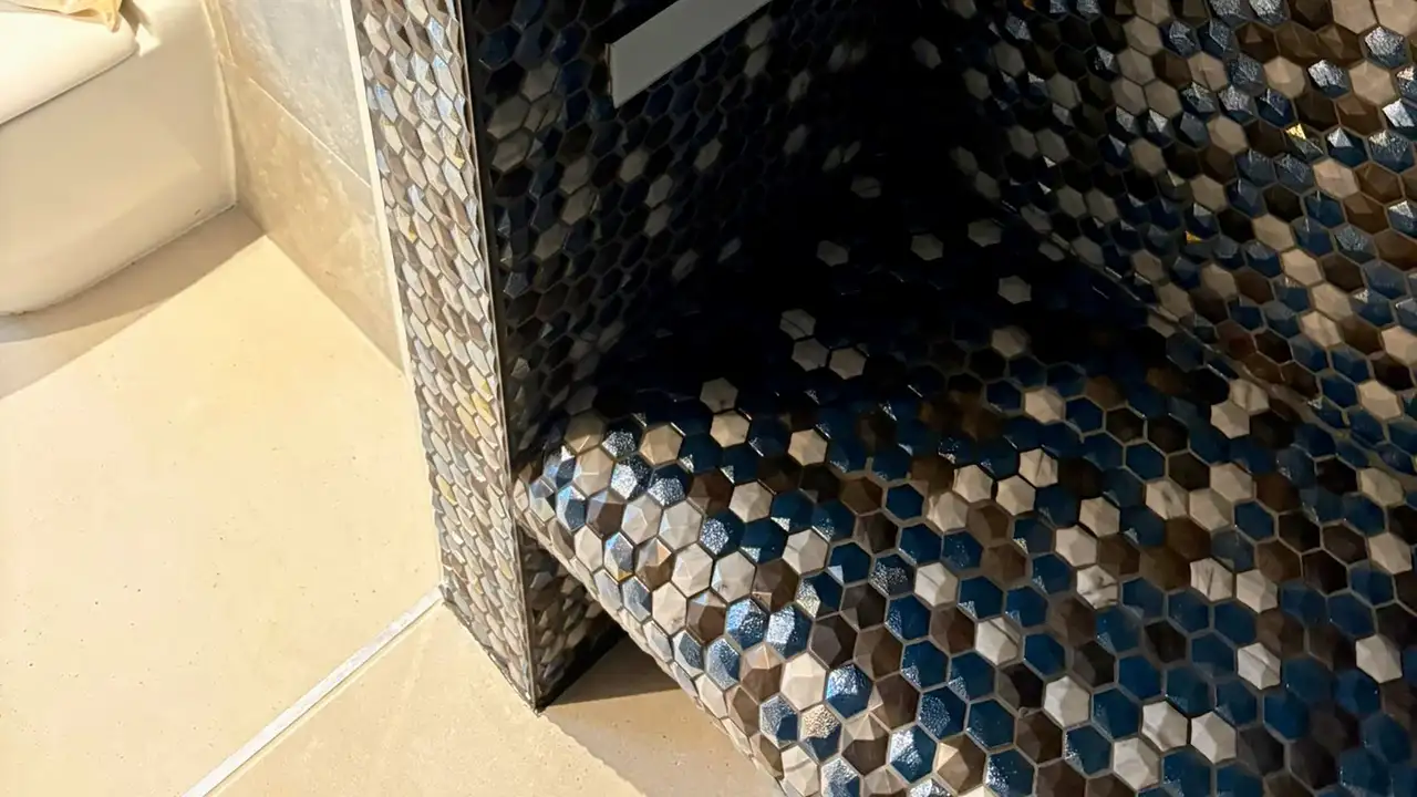 Bench in a shower tiled with blue, white and grey hexagon shaped tiles