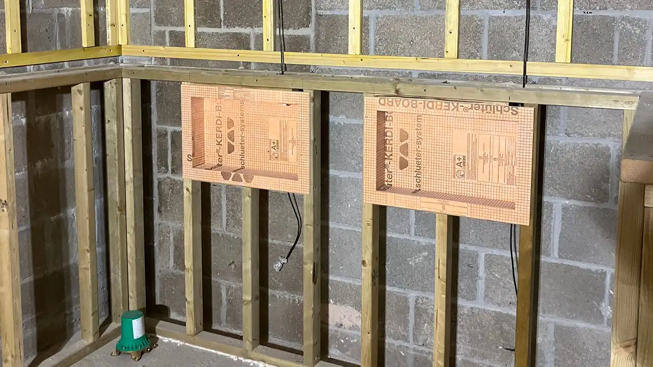 Bathroom wall under construction with two prefabricated Schl&uuml;ter niches installed on timberwood