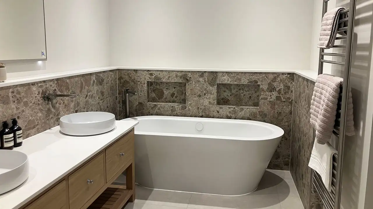 Modern bathroom with large marble tiles, a white bathtub, two wash basins and a large mirror on a white wall
