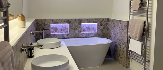 White bathtub with two illuminated niches in the wall above