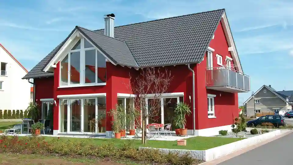 A passive house – with a red coloured façade and white-framed windows – is ideal for using DITRA-HEAT-E to supplement the heating system.