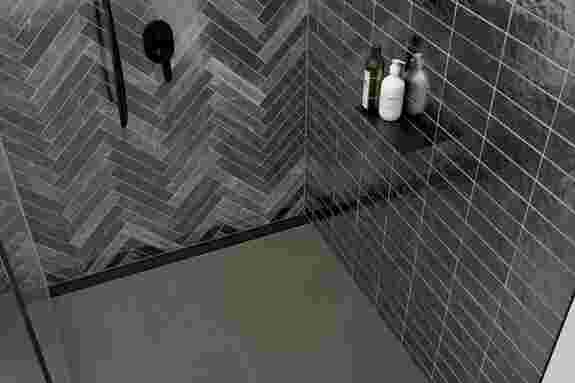 Dark, floor-level shower with matte black accents, KERDI-LINE-VARIO and SHELF in Trendline MGS.