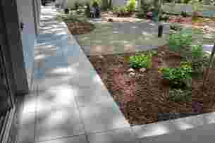 Edge strips in light grey terrace pavers between a house and an adjacent border
