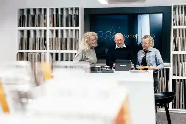 Salesroom with three people talking and Schlüter products displayed on both table and walls