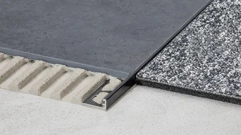 Covering finish on floor between tilework and carpet with a Schlüter-SCHIENE-TS in dark anthracite-finish