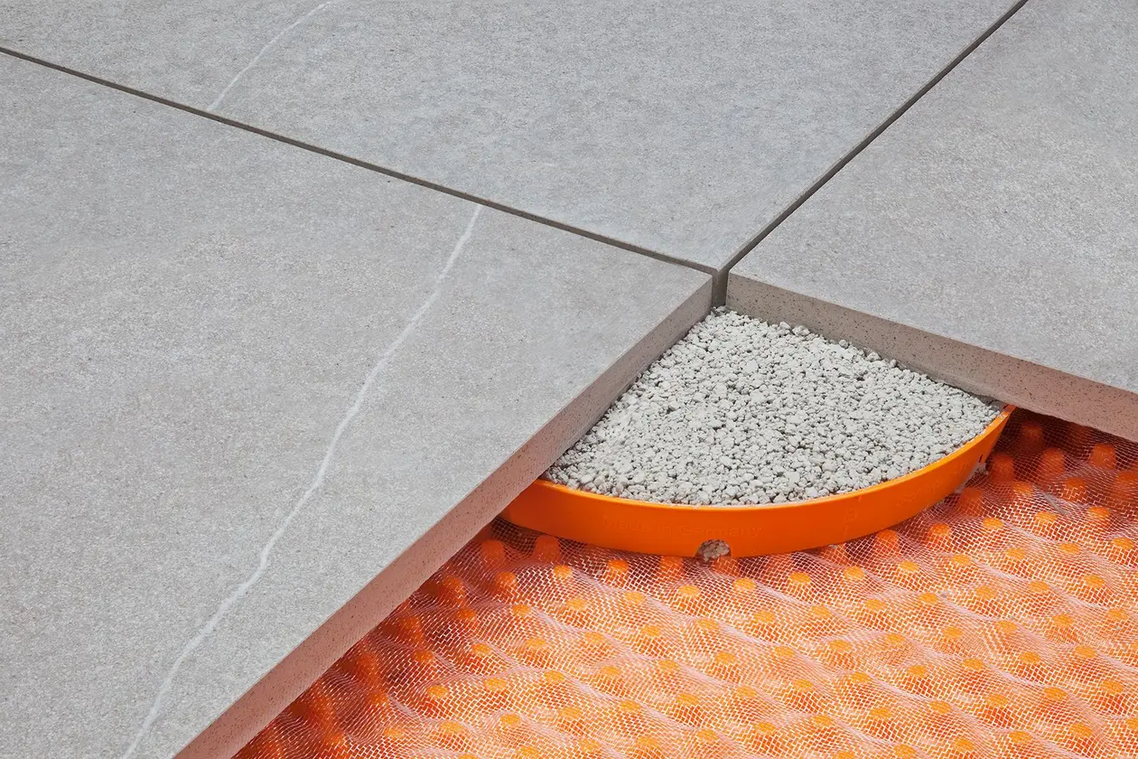 Three terrace pavers positioned with their corners over a mortar ring filled with mortar