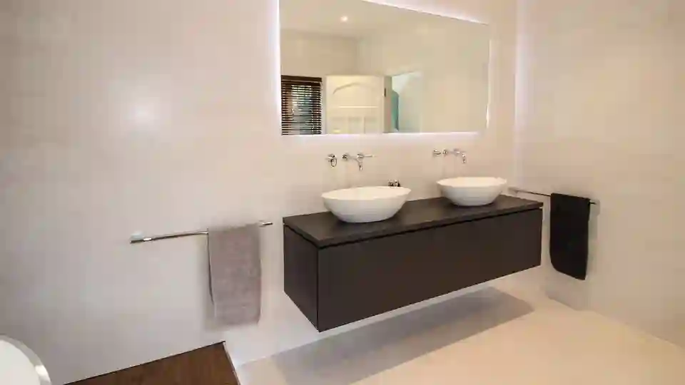 A wall hung vanity unit with two sinks and mirror above