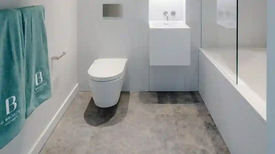 Modern bathroom featuring a wall hung wash basin and toilet in the centre and bathtub to the right