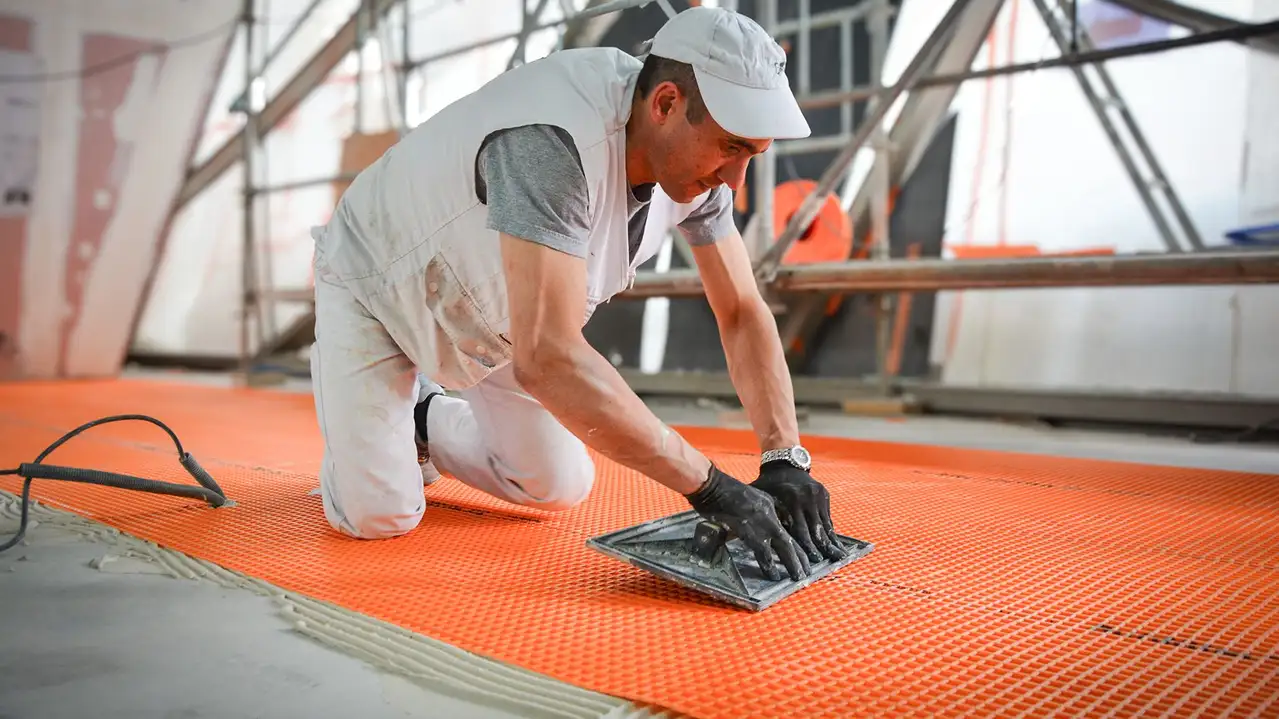 Egy burkoló leragaszt egy Schlüter-DITRA lemezt az Eiffel-torony építkezésén