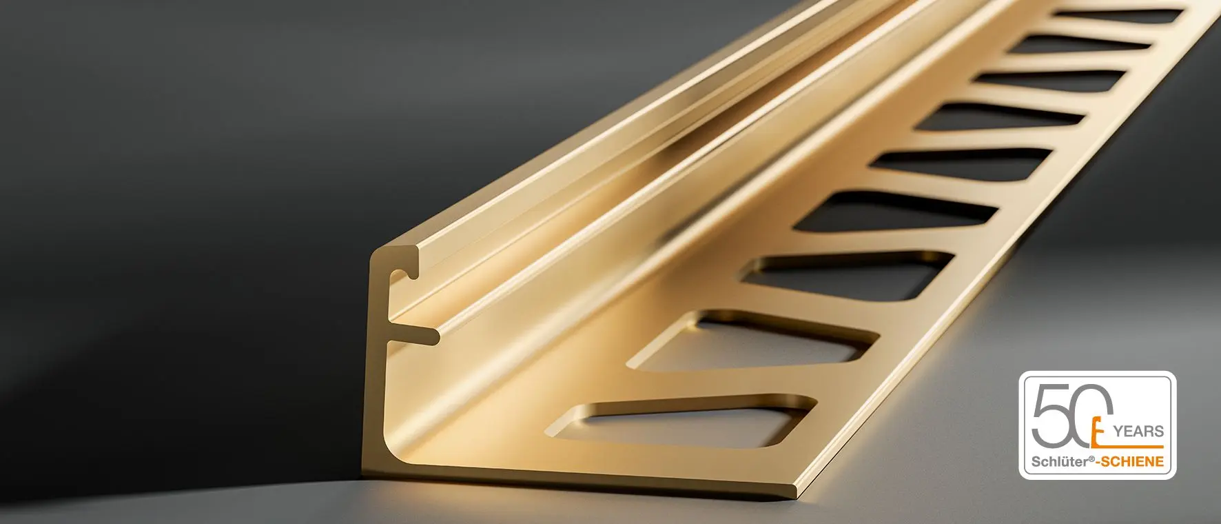 Primo piano del profilo di chiusura Schlüter-SCHIENE in ottone su sfondo grigio scuro