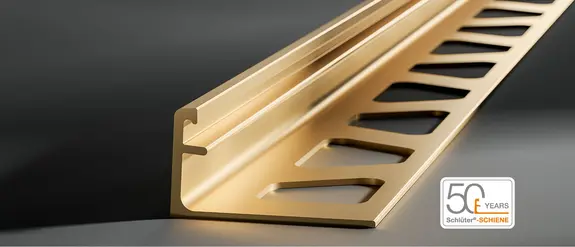 Primo piano del profilo di chiusura Schlüter-SCHIENE in ottone su sfondo grigio scuro