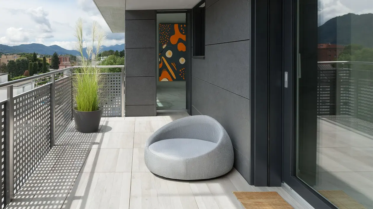 Balcone con piastrelle di grandi dimensioni color grigio chiaro e mobili in legno