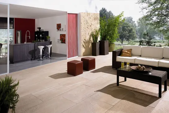 Una casa con un giardino adiacente e una terrazza con panca e open bar.