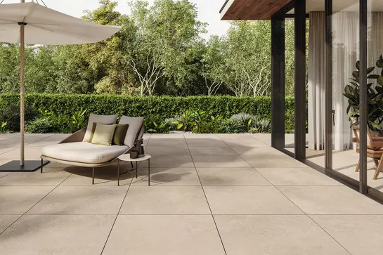 Terrazzo con grandi piastrelle beige, una sedia e un tavolo davanti a una grande porta vetrata.