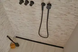 Doccia a filo pavimento con rivestimento ceramico color sabbia, rubinetto nero e scarico lineare nero matt Schlüter-KERDI-LINE-VARIO.