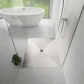 Bagno luminoso con doccia a filo pavimento, parete divisoria in vetro e vasca da bagno indipendente