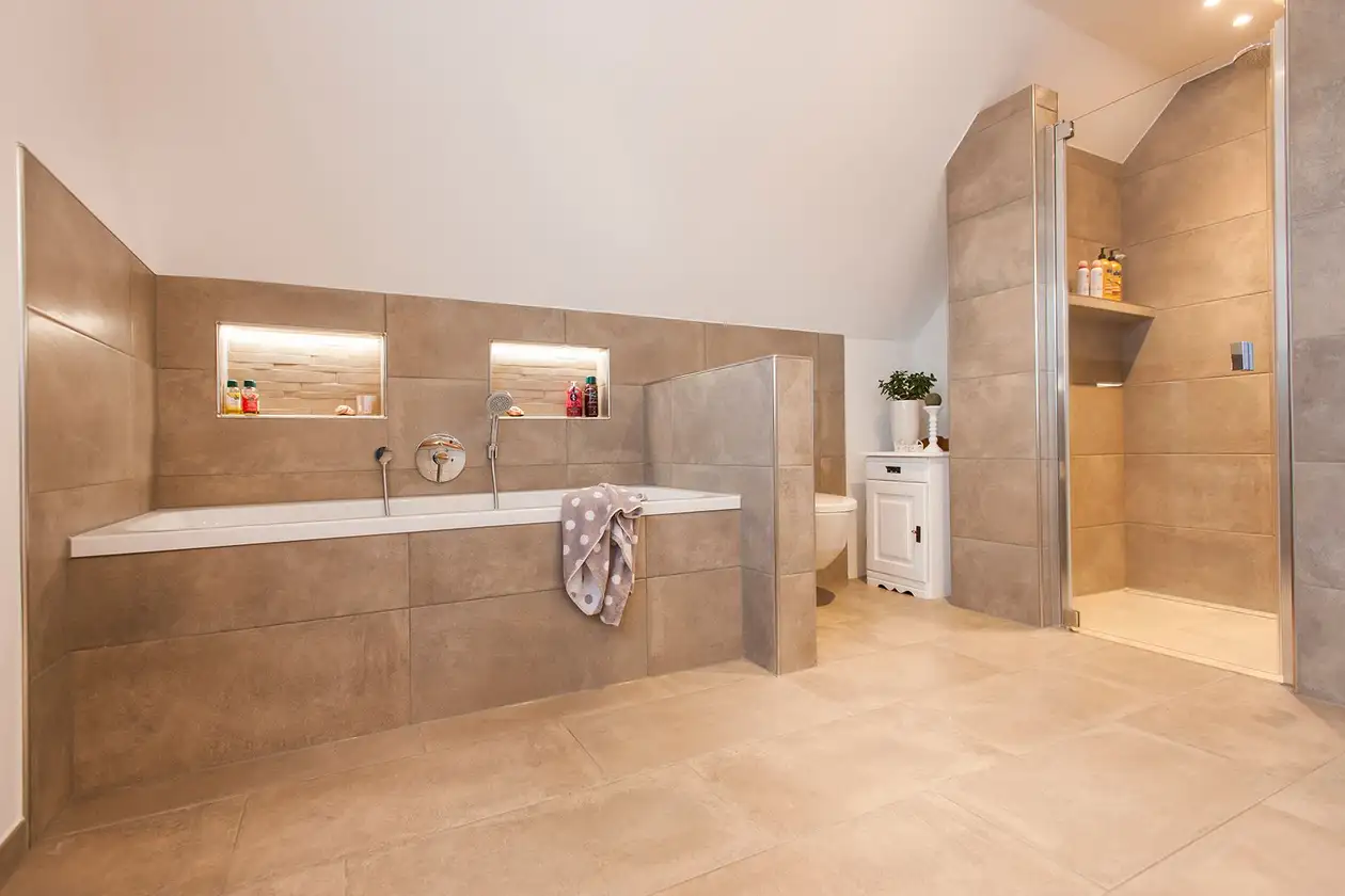 Vista di un bagno con grandi piastrelle luminose, vasca da bagno e doccia separata a filo pavimento