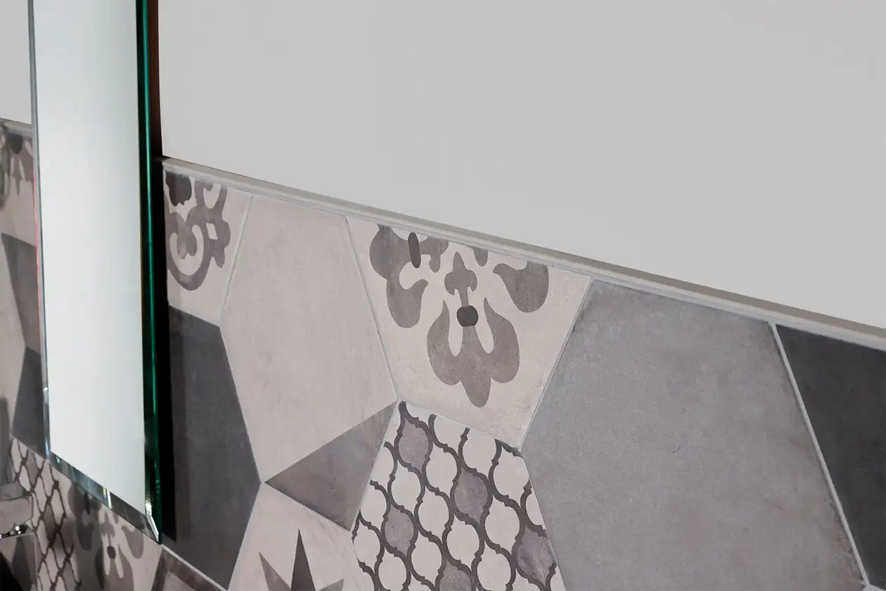 Chiusura di una superficie ceramica a mezz'altezza con un profilo JOLLY con finitura a rilievo grigio pietra