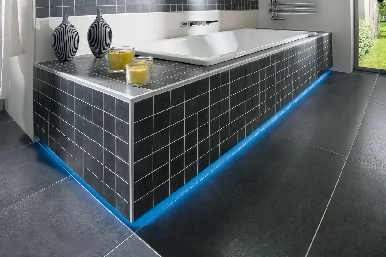 Bagno moderno con piastrelle scure e vasca da bagno illuminata