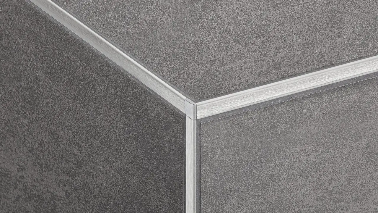 Particolare di un angolo del battiscopa rivestito in ceramica con profili paraspigolo Schlüter-JOLLY in acciaio inossidabile V2A spazzolato