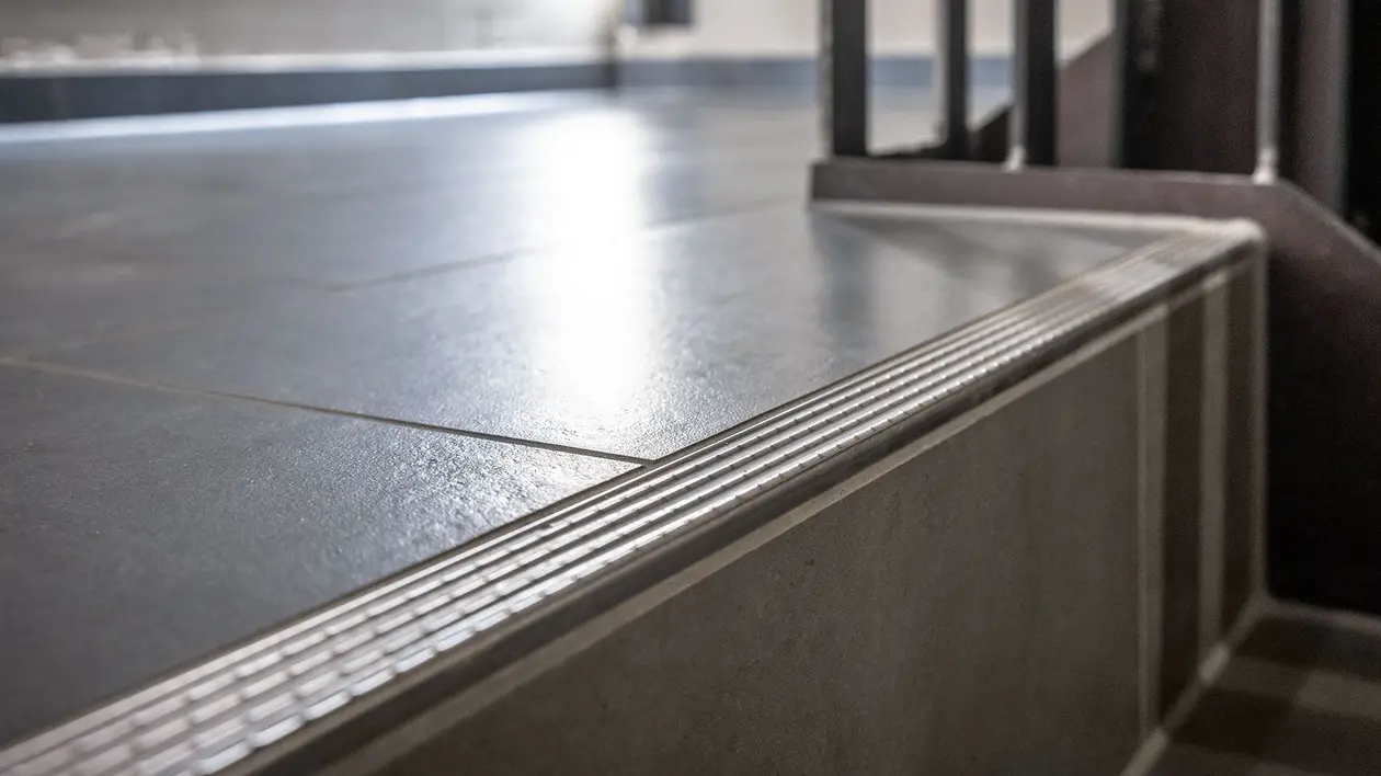 Un profilo Schlüter-TREP-E in acciaio inox che copre i bordi dei gradini della tromba delle scale dell'hotel Bretterbude.