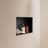 Matzwarte nis met poedercoating in een wand met beige tegels