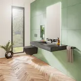 Vrij hangend en rolstoeltoegankelijk uitgevoerde wastafel in een lichte, lichtgroen betegelde badkamer