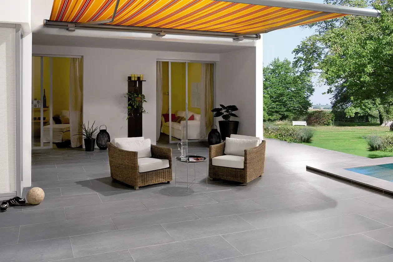 Op het terras van een huis met aangrenzende tuin zijn twee stoelen geplaatst.