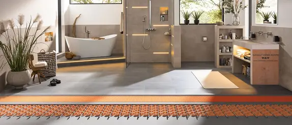 Grote, lichte badkamer met warme accentverlichting en blik op de opbouw van de vloerverwarming BEKOTEC-THERM onder de tegels