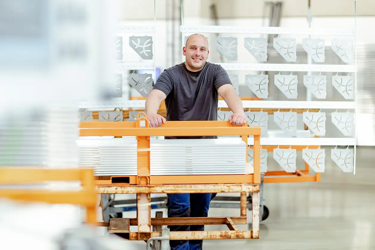 Mannelijke medewerker van Schl&uuml;ter-Systems staat voor gecoate profielen.