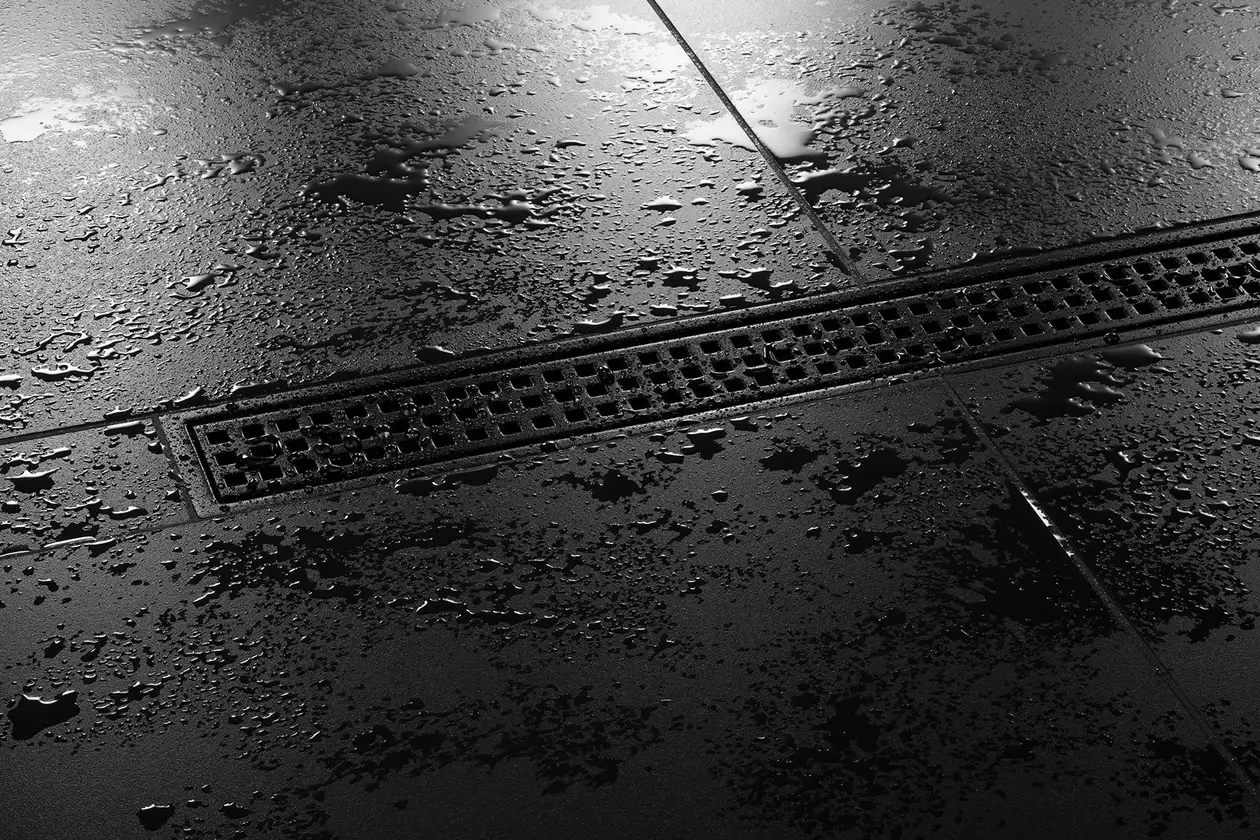 Zbliżenie na odpływ liniowy Schlüter-KERDI-LINE-B SQUARE w kolorze czerń grafitowa matowa w kabinie prysznicowej bez brodzika wyłożonej czarnymi płytkami.