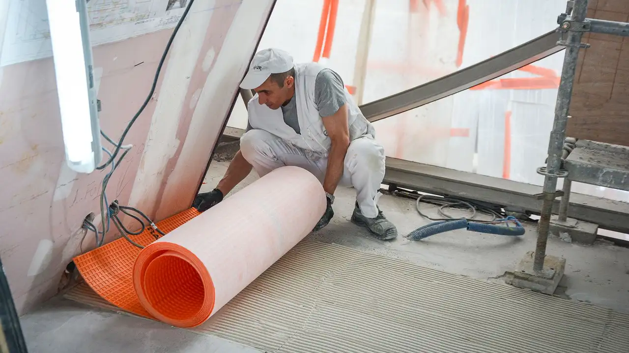 Um ladrilhador estende Schlüter-DITRA no local de construção da Torre Eiffel
