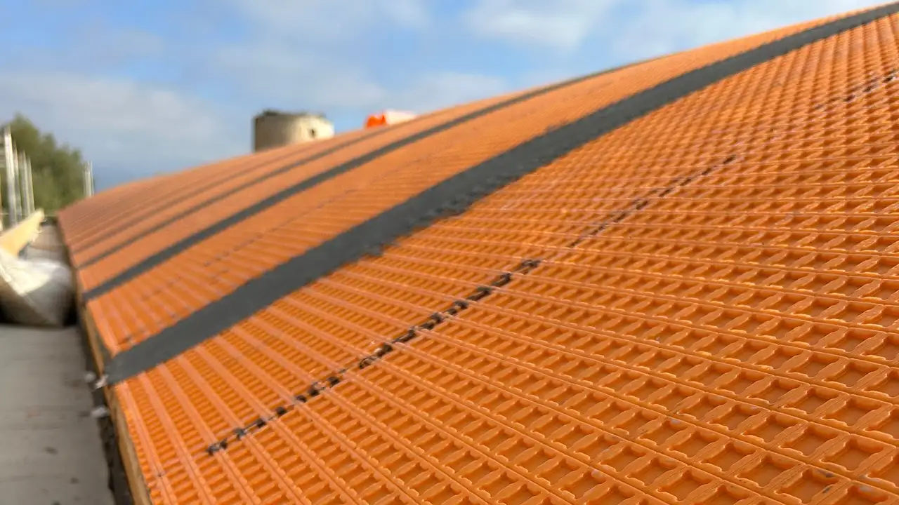 Membrana de desacoplamento laranja DITRA com cavidades quadradas para aplicar o cimento cola para cer&acirc;mica.