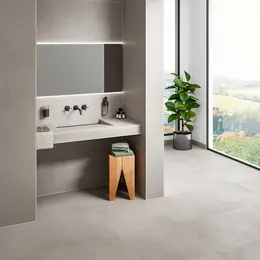 Móvel para lavatório numa casa de banho com azulejos com a aparência de betão e os perfis de canto adequados com o revestimento TRENDLINE em cinzento claro