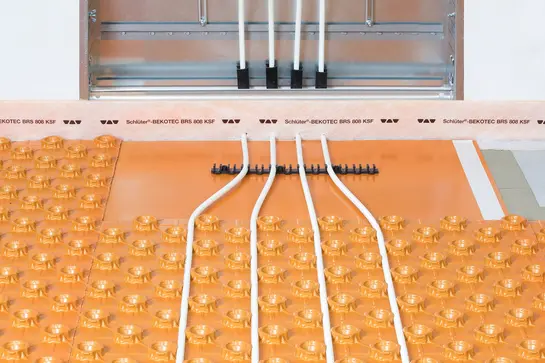 Vários componentes do sistema do piso radiante BEKOTEC-THERM instalados na transição entre o pavimento e a parede