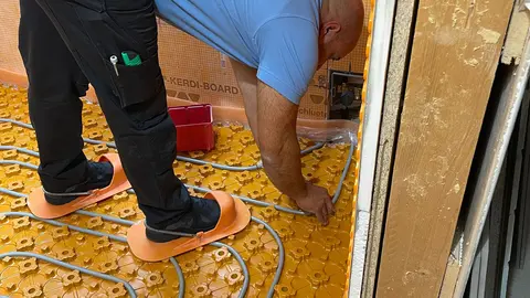 Um instalador coloca os tubos para o pavimento cerâmico climatizado BEKOTEC-THERM-EN F.