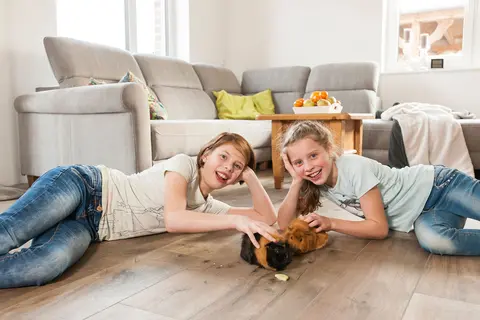 Tv&aring; flickor ligger p&aring; golvet som v&auml;rms upp med BEKOTEC-THERM.
